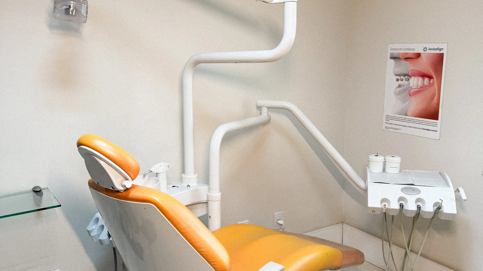 Consultório com cadeira odontológica laranja e luz natural