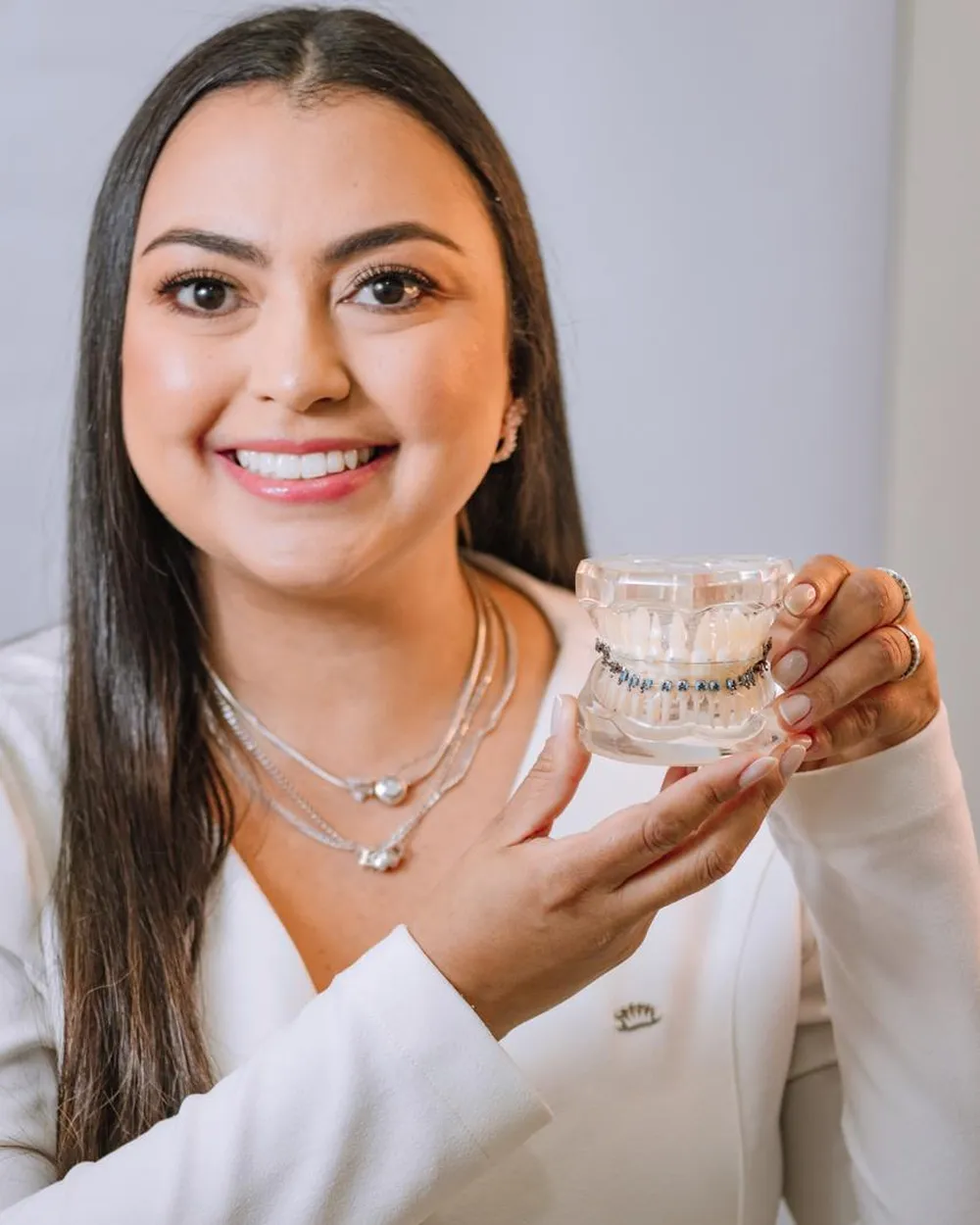 Dra. Rafaela Pierre, ortodontista, segurando modelo de arcada com aparelho